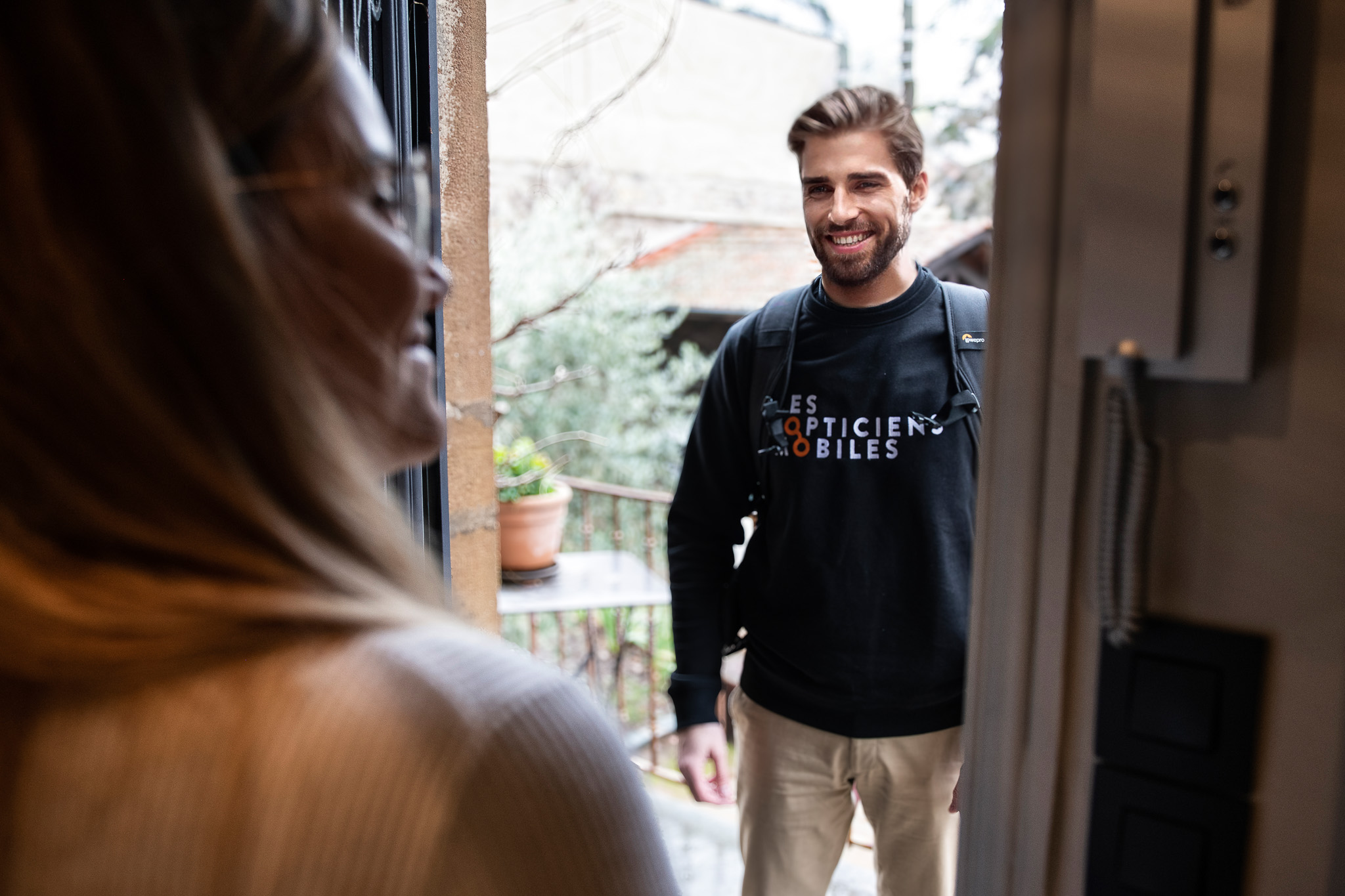 Opticien mobile souriant arrivant chez un client. Professionnel de santé à domicile certifié NF 