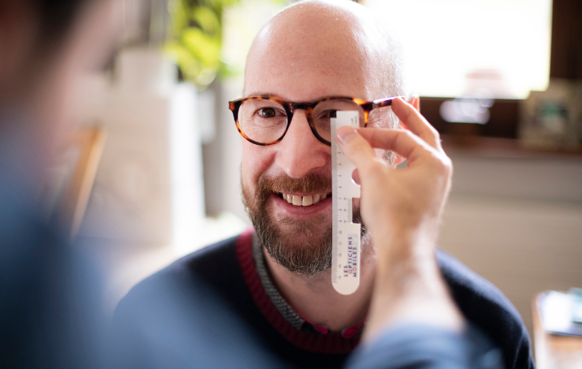 Un client teste sa vue avec des verres de lunettes unifocaux lors de la visite d'un opticien à domicile.